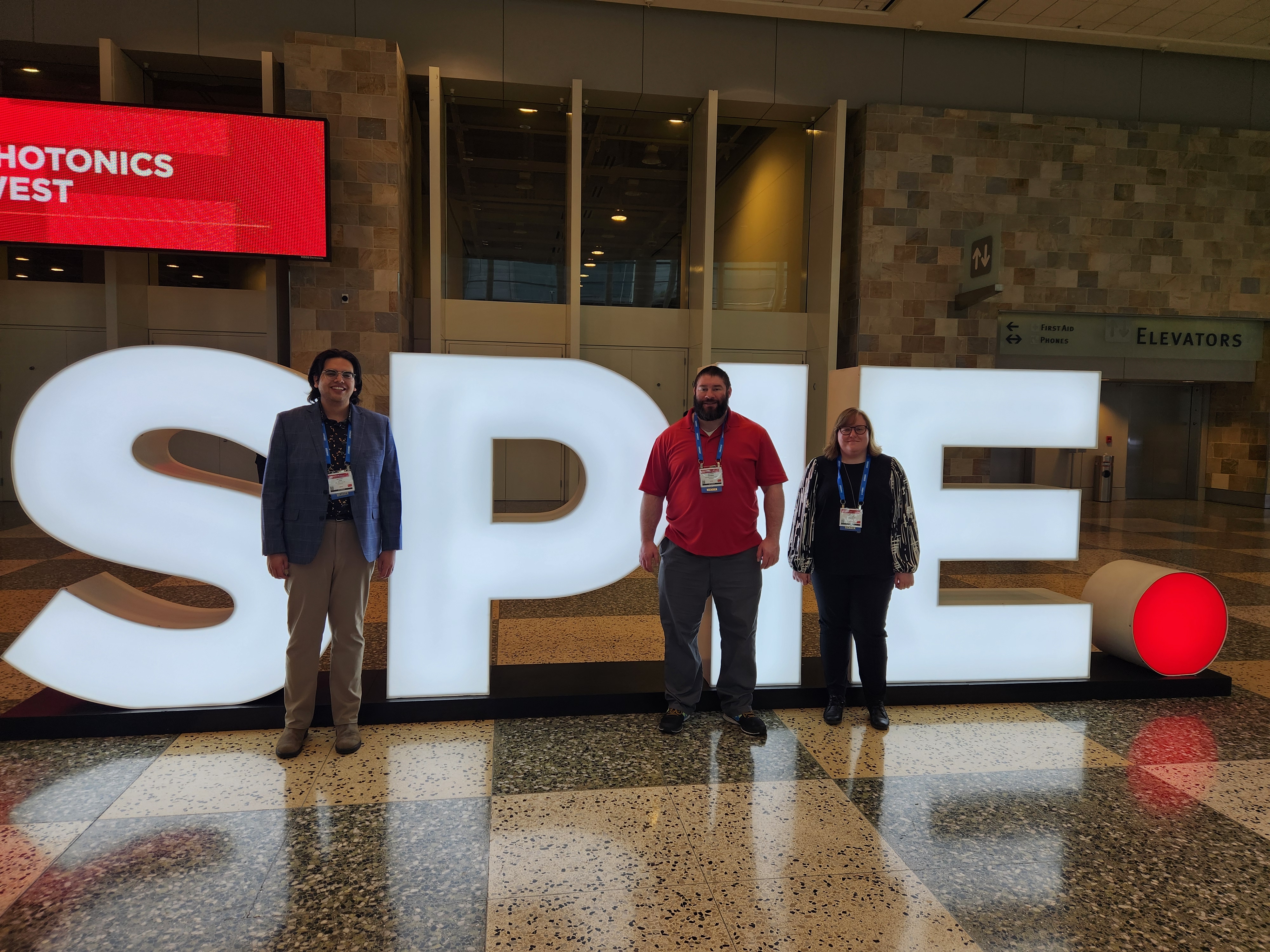 Zach Lakin, Matt Goodman, and Corey Pearson standing in front of an SPIE sign.