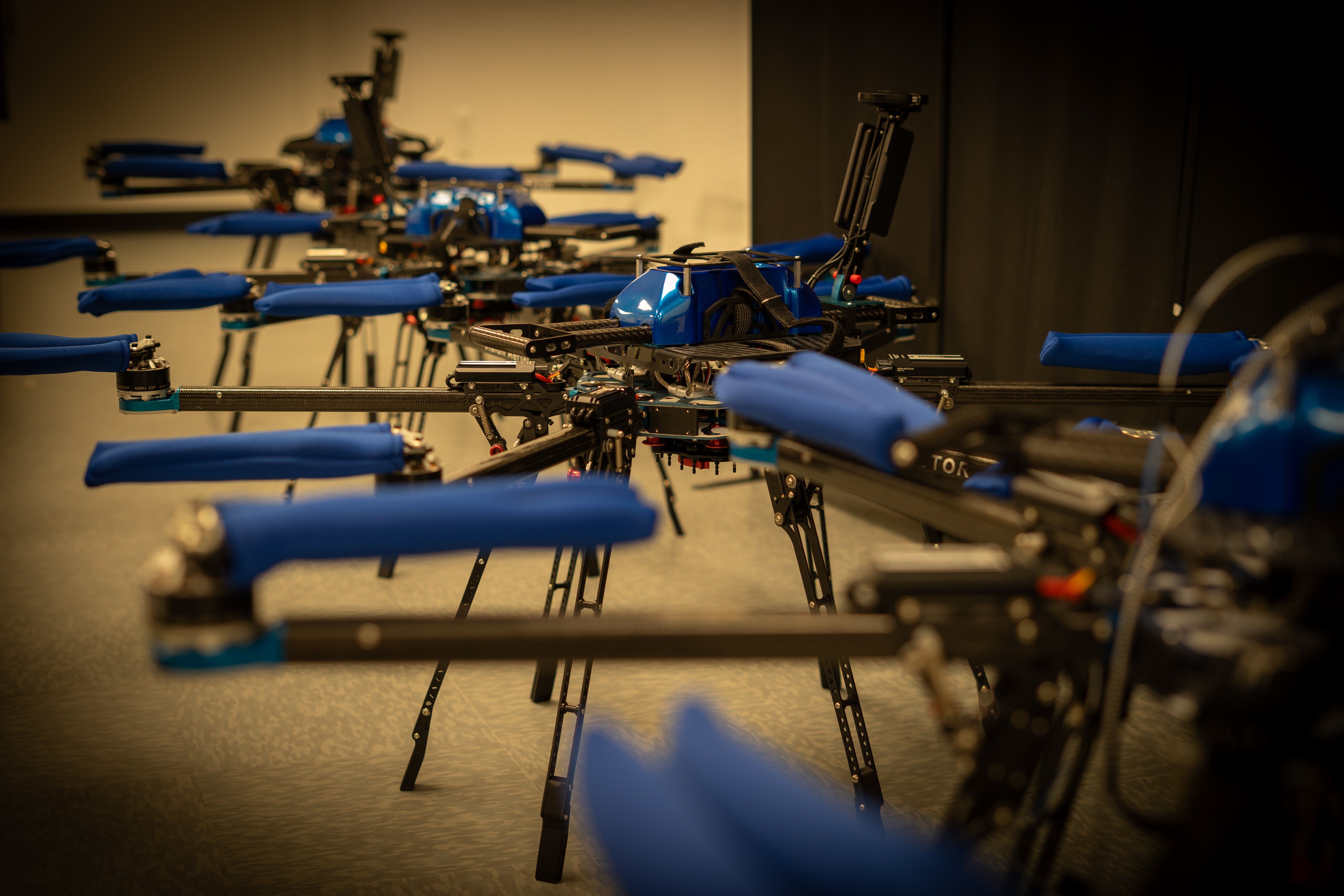Mulitple drones in a line sitting on the floor of a lab