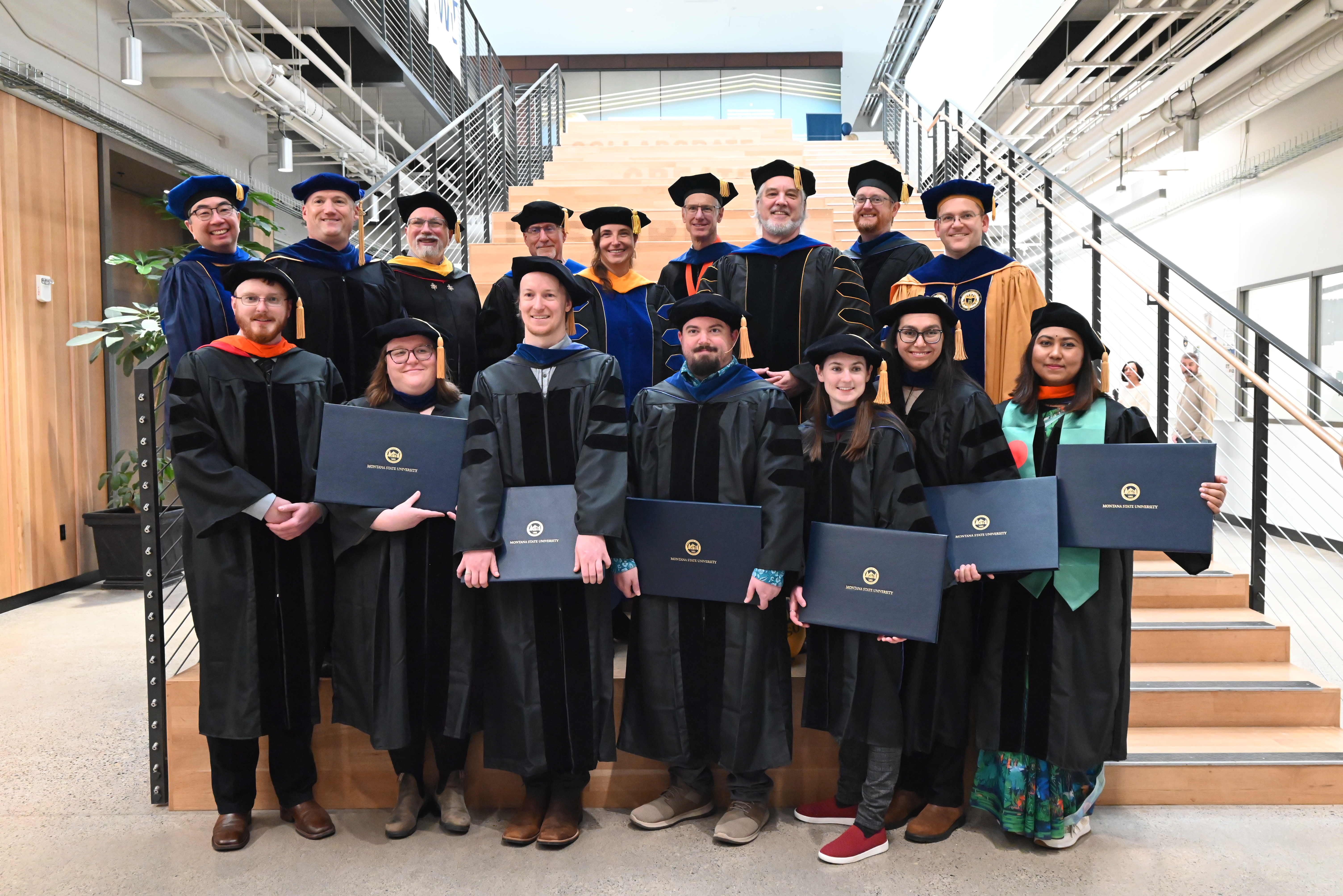 Eight PhD graduates stand in front of ECE and Physics faculty
