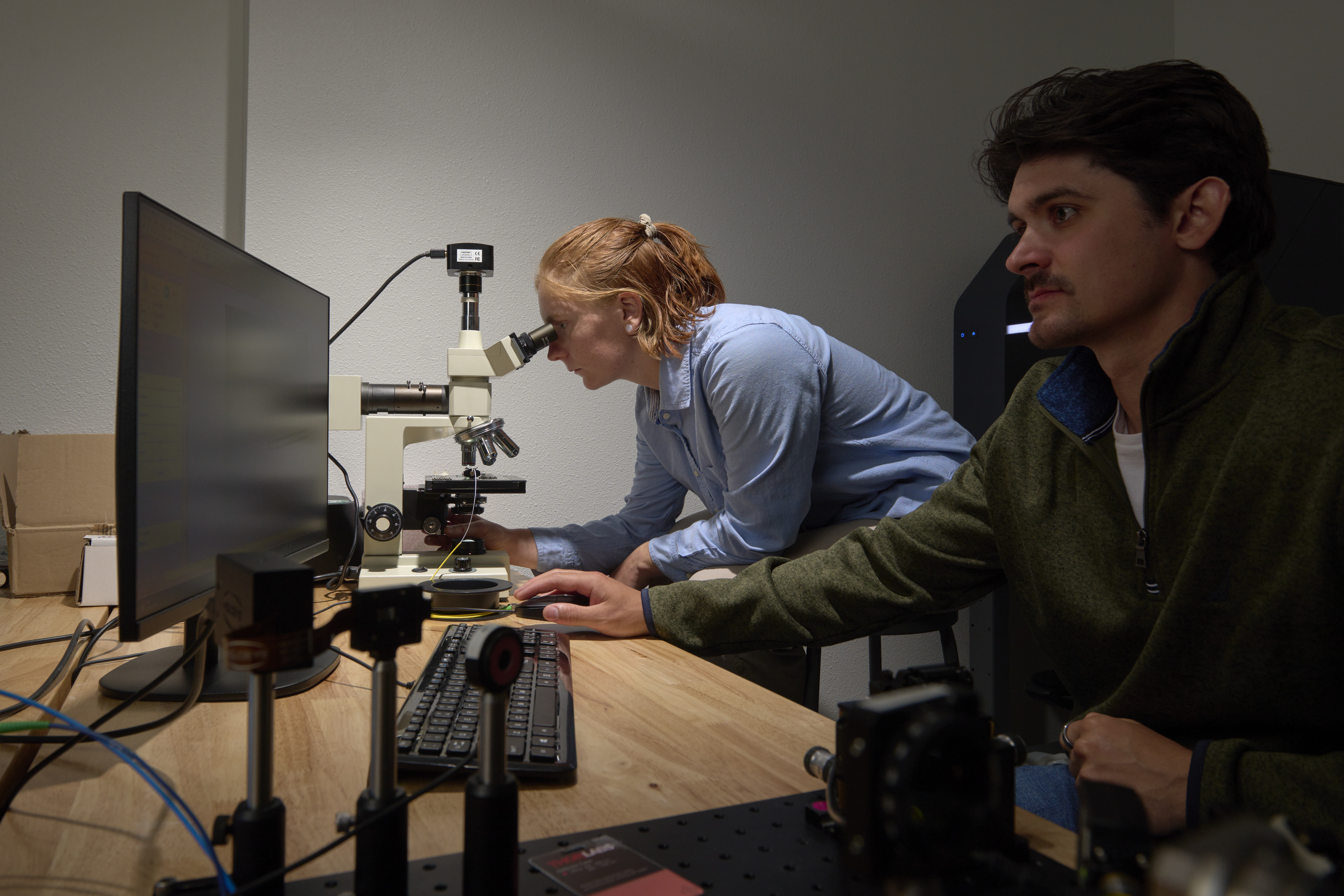Undergrad Kat and staff member Sam look at a micro-printed structure at a microscope
